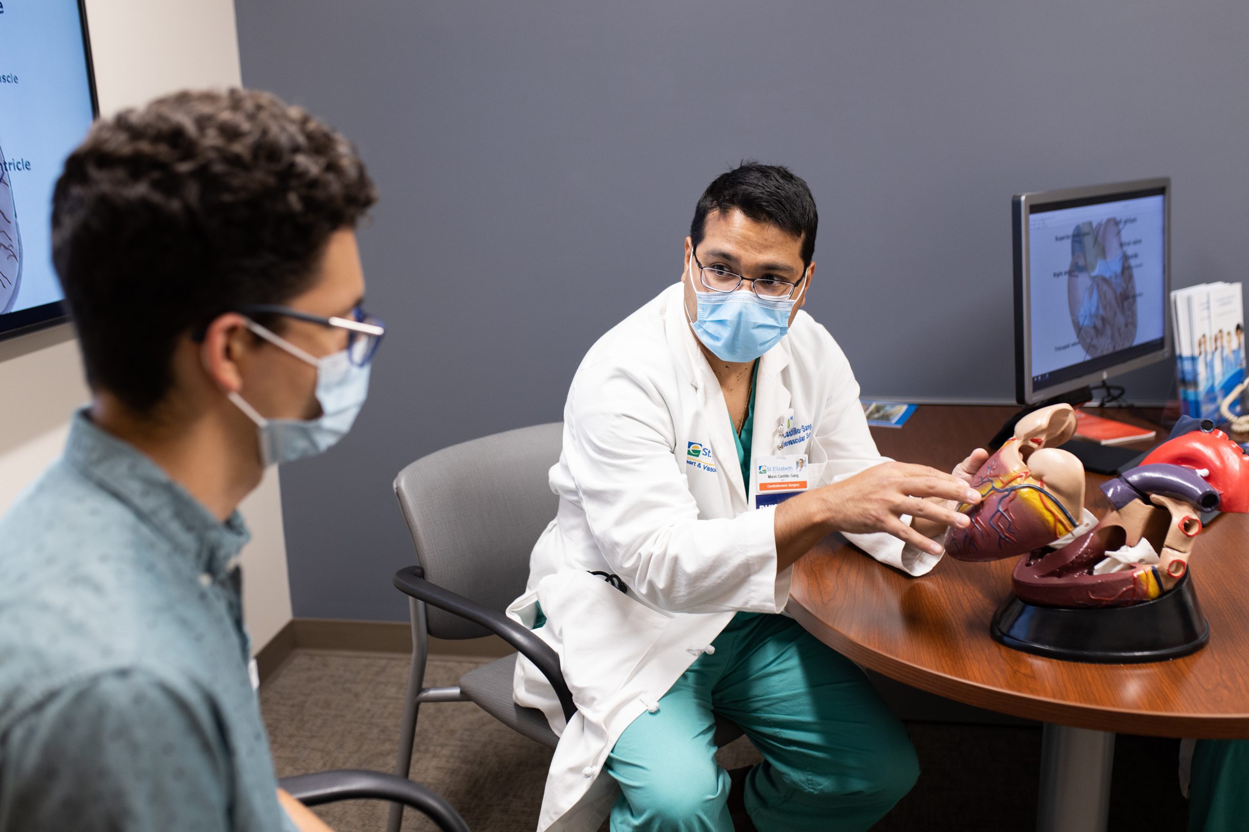 Dr Castillo Sang Doctor shows a patient a model of the heart organ.