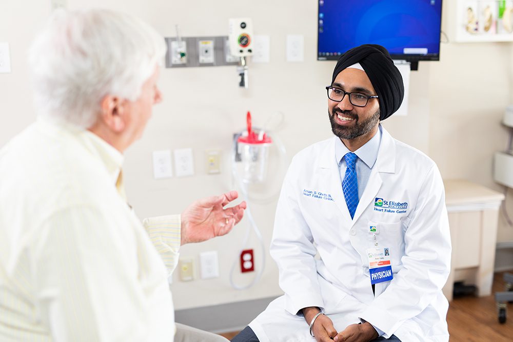 Dr. Aman Ghotra Heart Doctor speaks with patient in medical office.