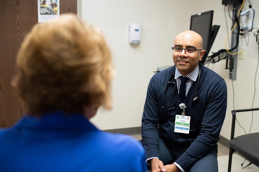 Dr. Ivan Bedoya speaks with a patient in a medical office.