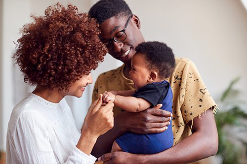 Loving Parents Playing With Newborn Baby At Home