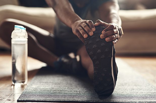 Young man stretching his legs while exercising at home