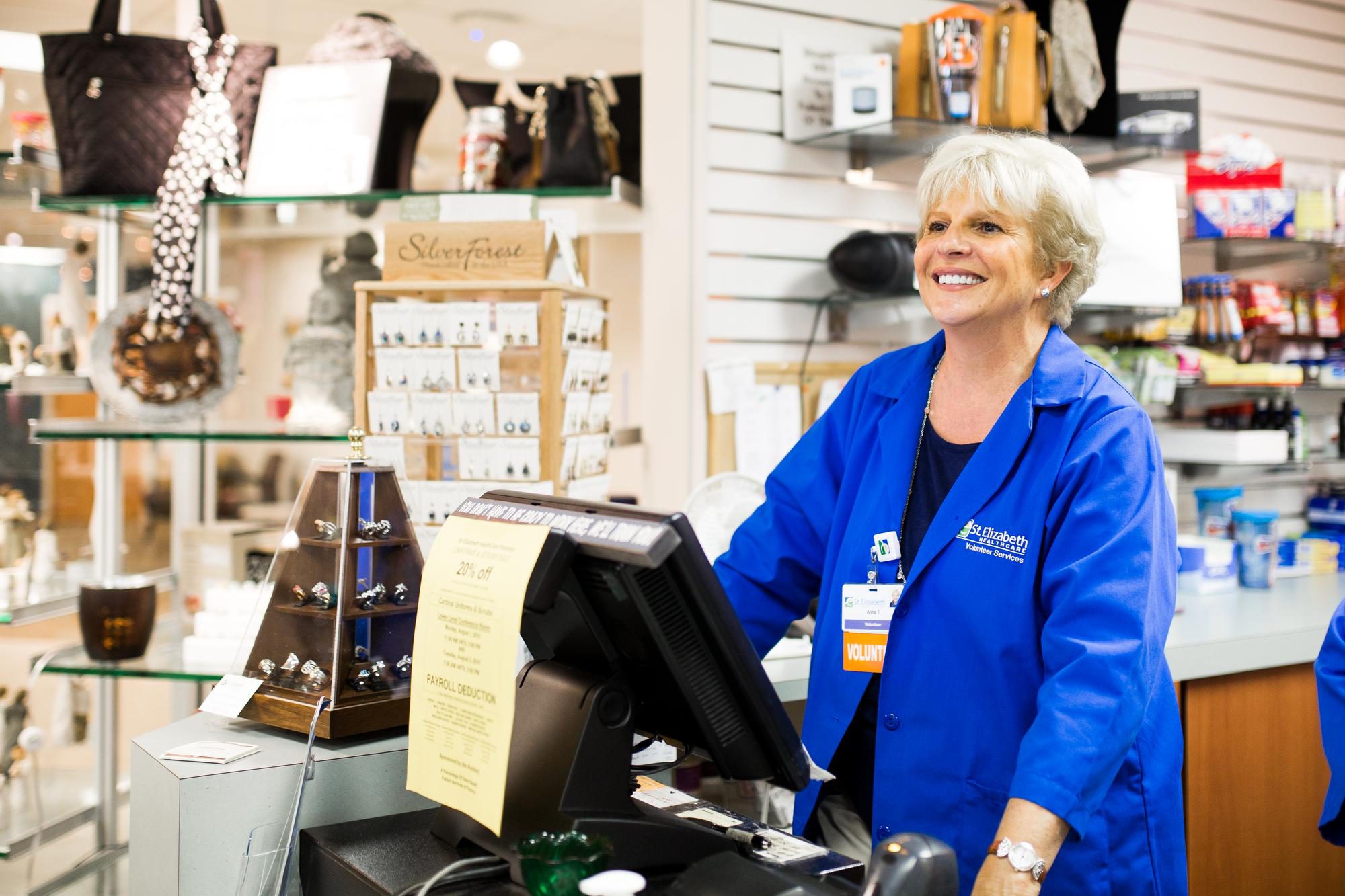 A volunteer stands behind a cash register at the St. Elizabeth Gift Shop
