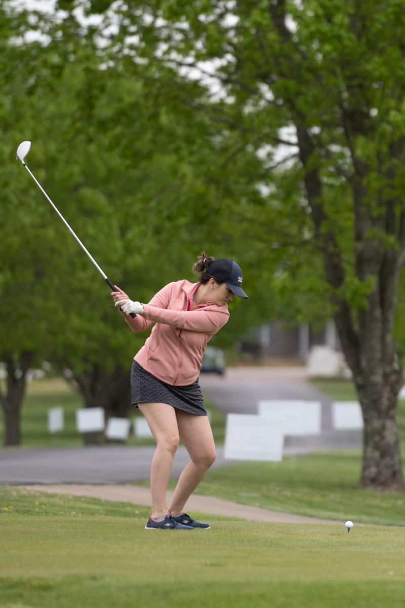 Woman swings at a golf ball