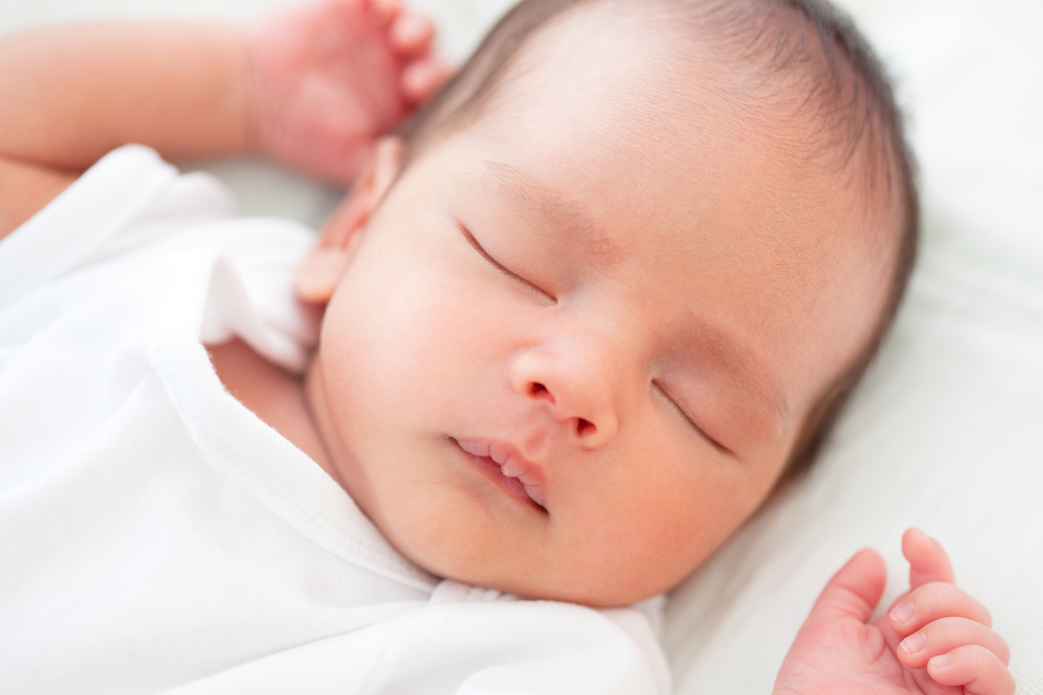 Sleeping newborn baby in white