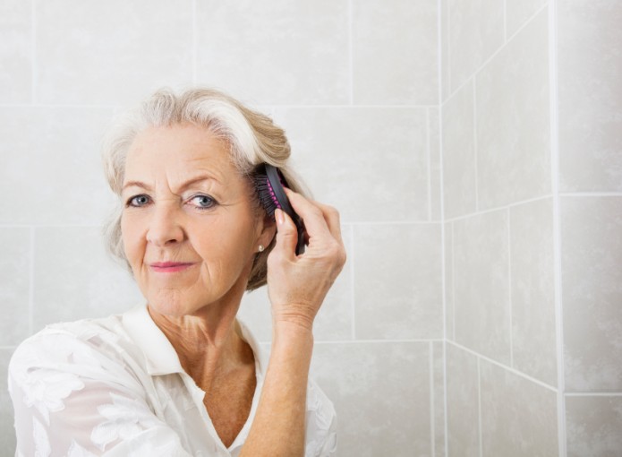 Portrait of senior woman brushing hair in bathroom Healthy Headlines