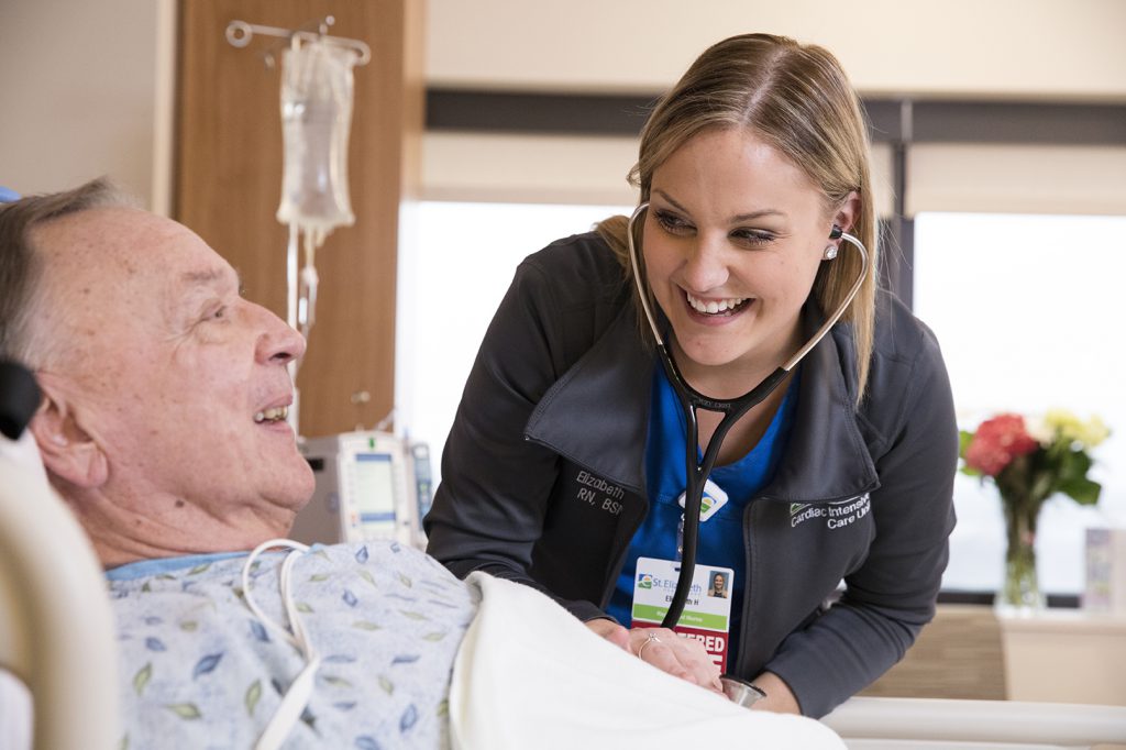 Smiling ICU nurse examining happy patient