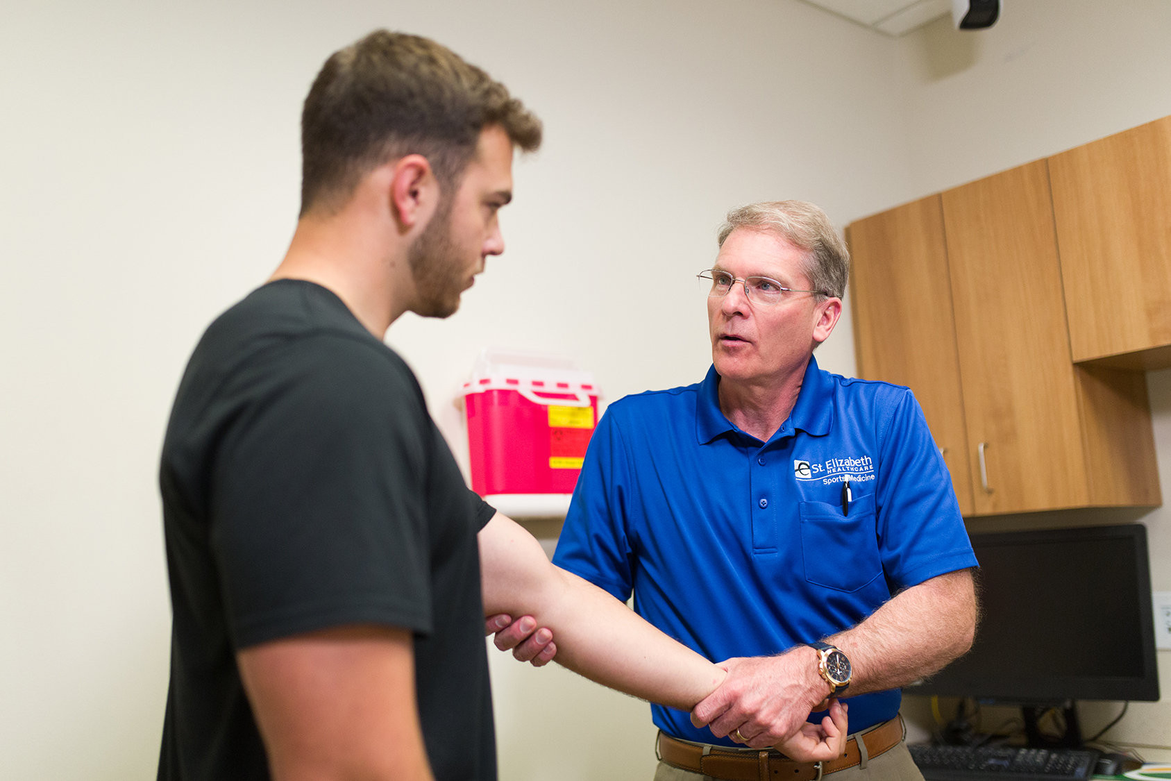 Dr. Miller examines male athlete's arm