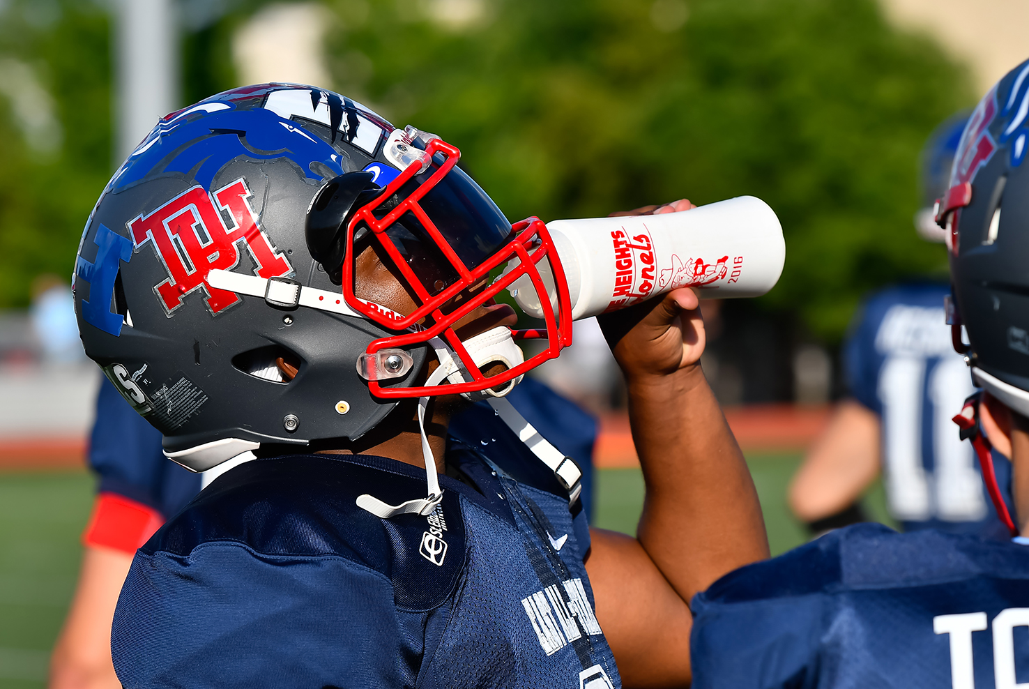 Football player drinking water on hot summer day