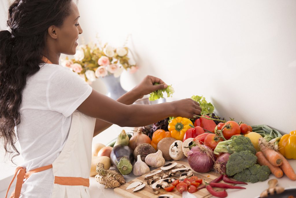 Woman smiling while preparing meal with healthy, fresh produce