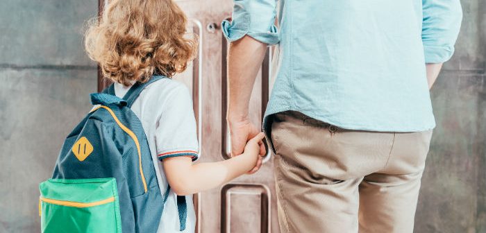 Child wearing backpack holding parent's hand