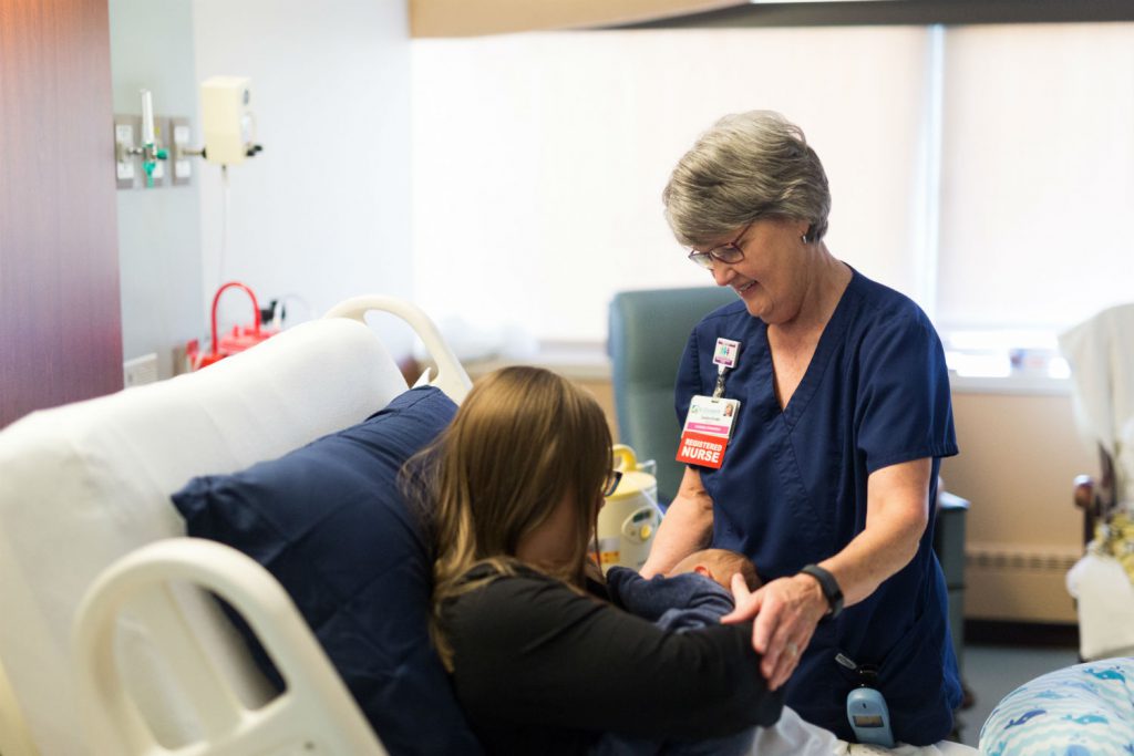 Nurse helping new mother breastfeed