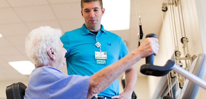 Physical Therapist helps older female patient exercise