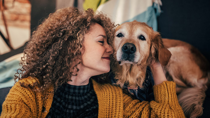 Woman with curly hair hugging old golden retriever