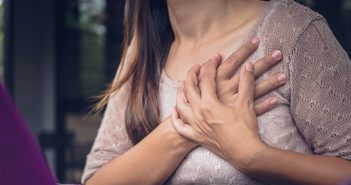 Young woman grabbing chest because of chest pain.