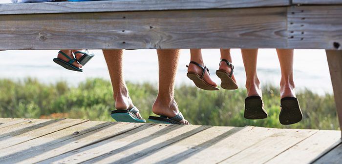 Family sitting on bench at the beach wearing flip flops.