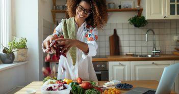 African American woman cooking with fresh vegetables in bright kitchen