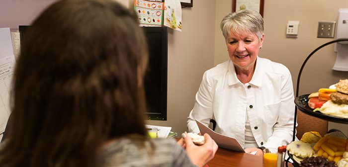 Dietitian speaking to patient about healthy options at a desk in an office.