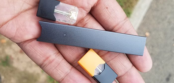 Male holding piece of JUUL, similar look to USB drive.