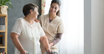 Same-day joint replacement gets you moving faster Smiling nurse helping senior lady to walk around the nursing home