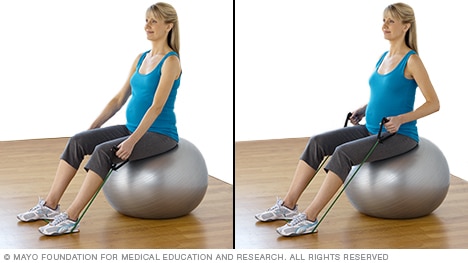 Pregnant person doing a seated row with resistance tubing
