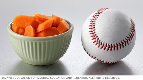 Half a cup of cooked carrots next to a baseball.