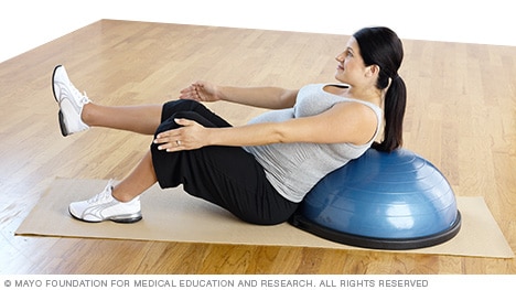 Pregnant person doing a v-sit supported by a balance trainer