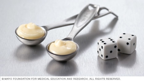 Two teaspoons of mayonnaise next to dice.