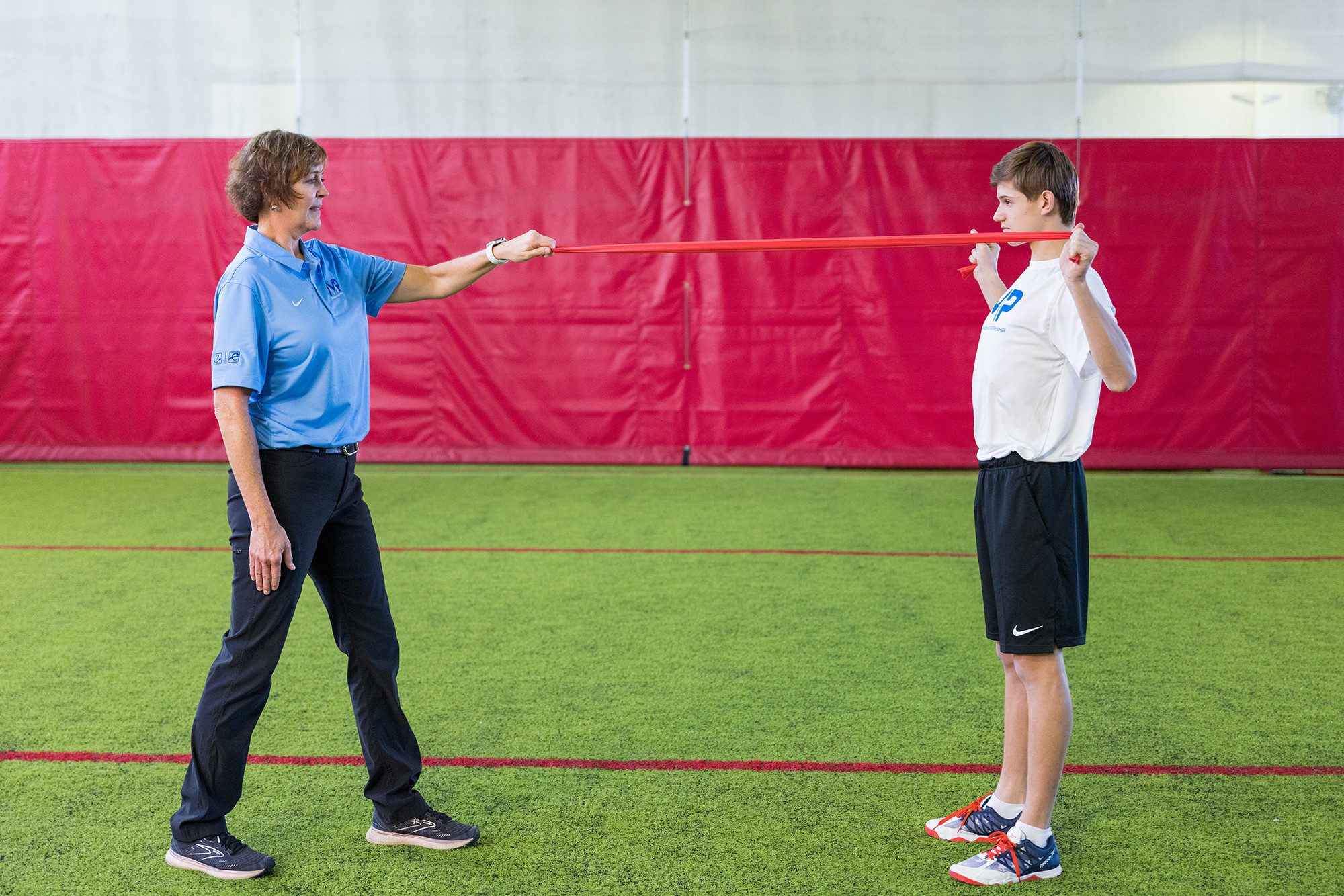 A Trainer and student athlete exercise with a band.