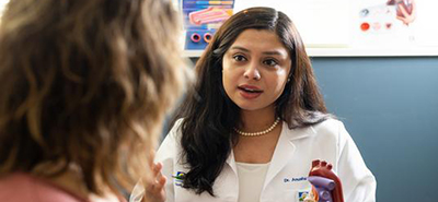 A heart doctor explains the heart to a patient using a plastic heart model figure. 
