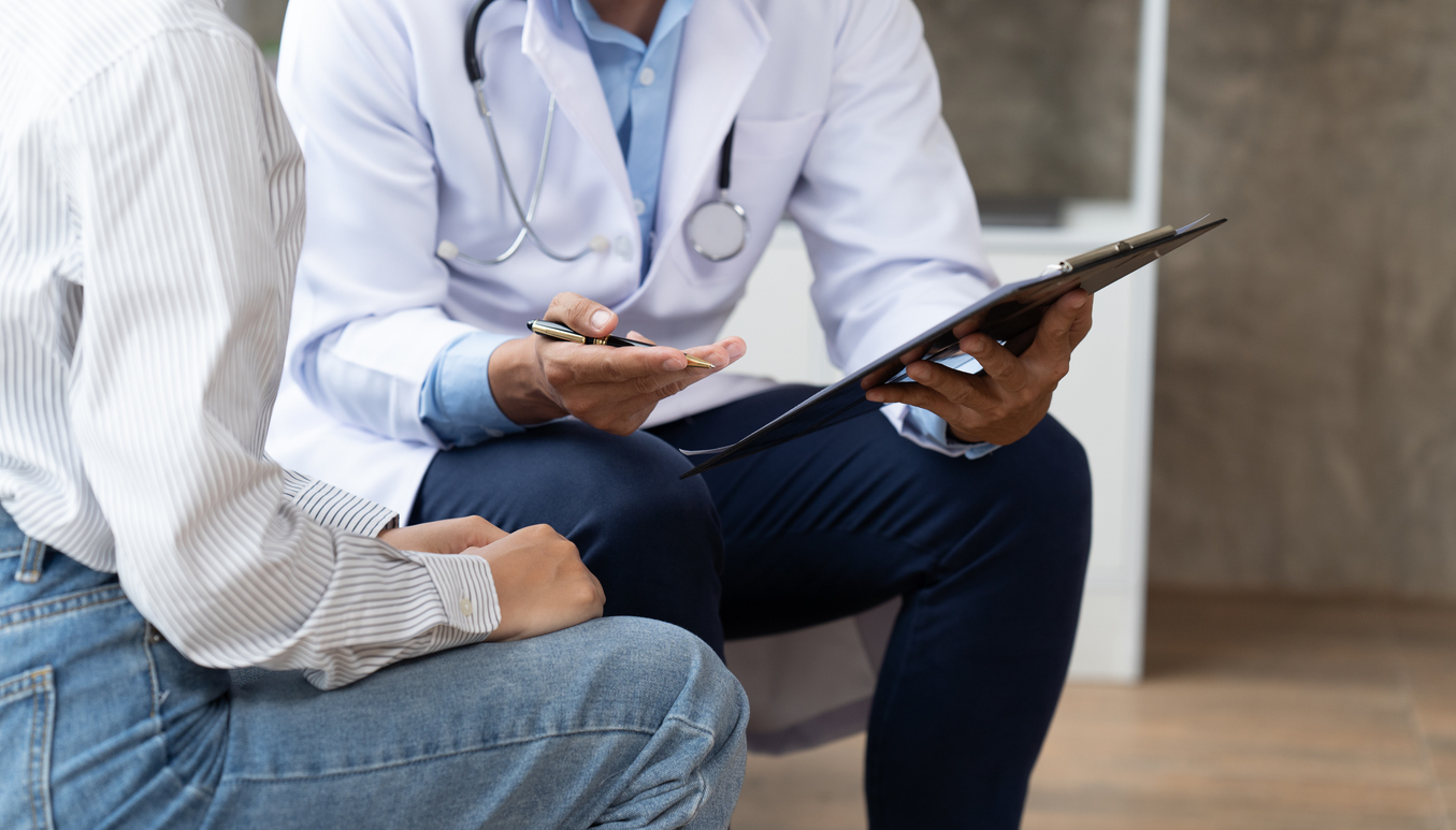 Doctor and patient sitting and talking at medical examination at hospital office.
